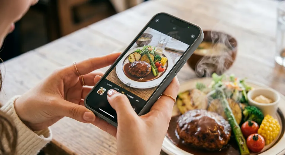 スマホで料理を撮影する女性